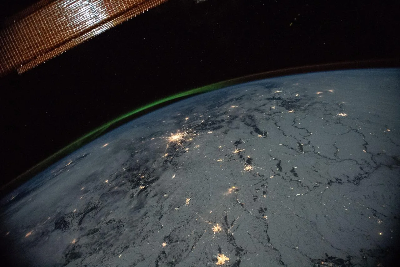 Earth at night photographed from the International Space Station, with part of the spacecraft in view. Context photograph, not an orbit prediction.
